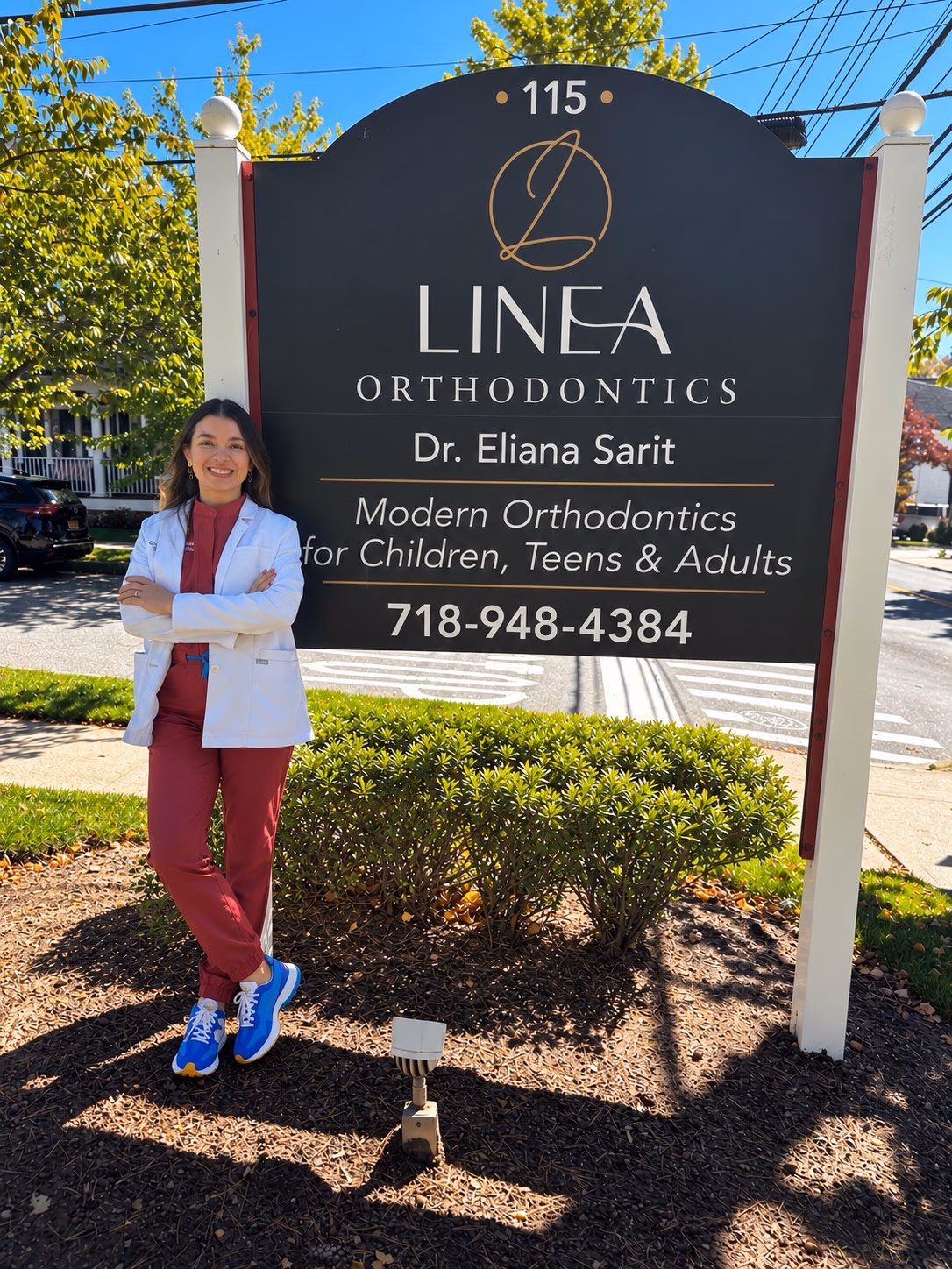 Dr. Eliana Sarit beside the Linea Orthodontics sign at 115 Seguine Ave, Staten Island