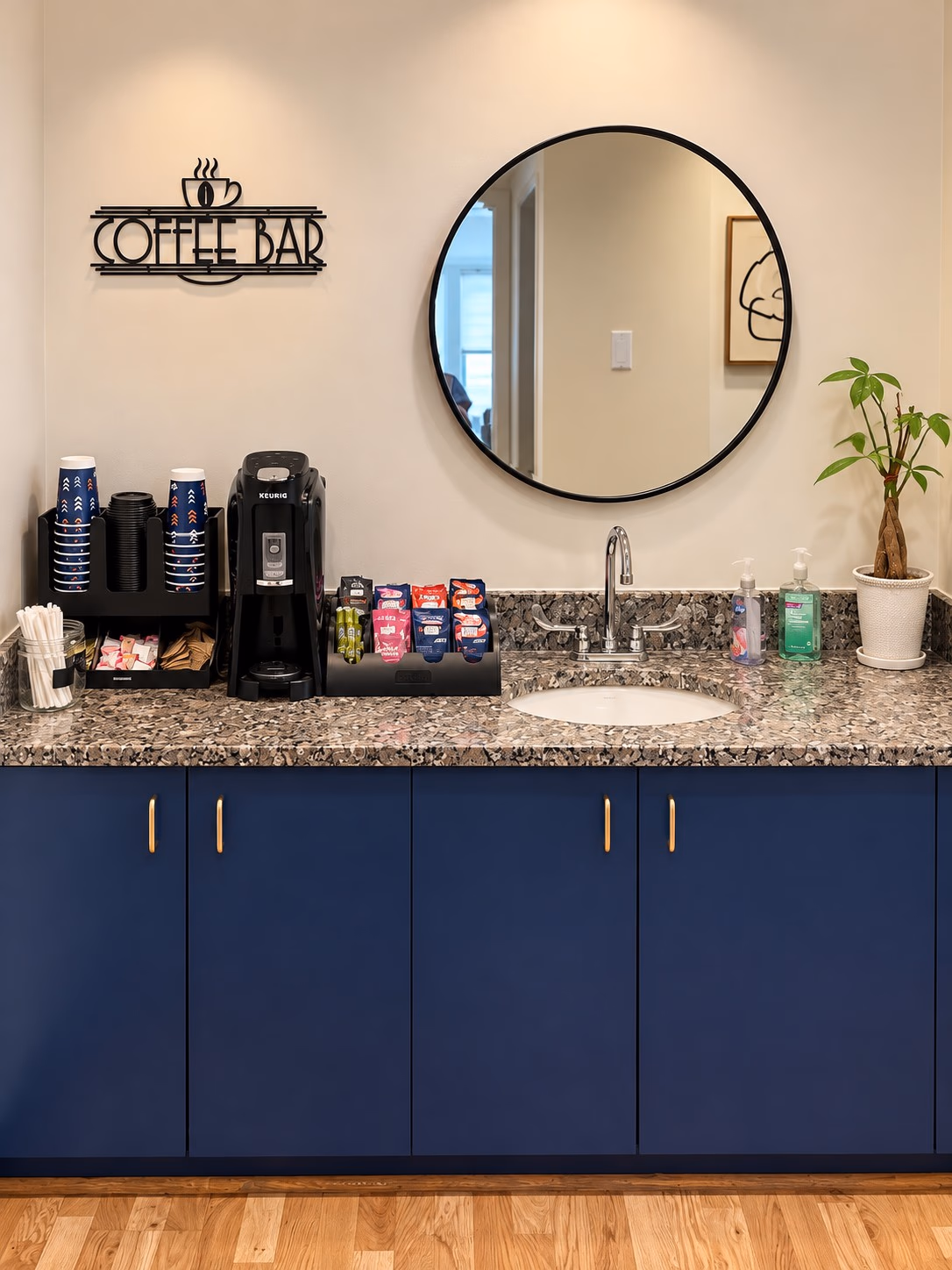 Coffee bar with a round mirror and navy cabinets at Linea Orthodontics
